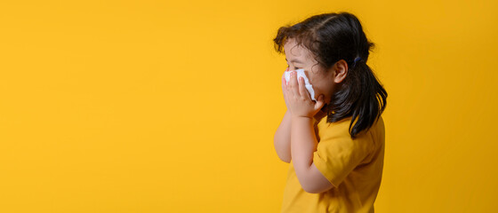 Little asian girl sick and sad with sneezing on nose and cold cough on tissue paper because weak or...