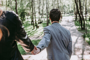 guy leads the girl by the hand to the park. A loving couple walks in the spring together. follow me