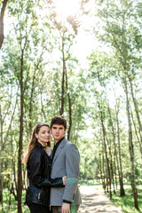 Happy young girl laughing happily while standing next to her beloved boyfriend in spring in the park. guy and the girl bonding in love. Happy couple smiling having fun while relaxing outdoors.