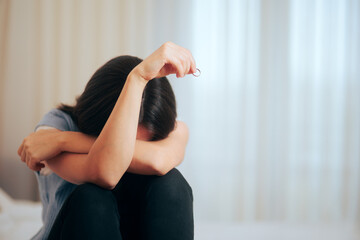 Depressed Woman Holding Wedding Ring Crying after Divorce