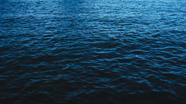 The deep serene sea. Dark blue ocean waves background. Calm water surface. Nature backdrop.