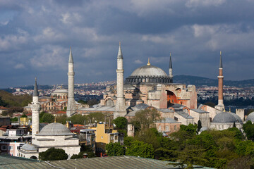 Istanbul, Turkey: Minarets of a local mosque and the orange-walled Hagia Sophia Museum rise into a...