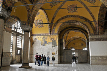 Istanbul, Turkey: Visitors view a damaged Deesis mosaic in Hagia Sophia Museum's upper gallery, its high vaulted yellow ceiling supported by marble pillars and decorated with paintings.