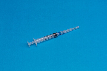 Disposable syringe on a blue background.