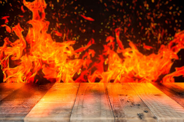 Rustic wooden table with flames and fire effect on dark blurred background.