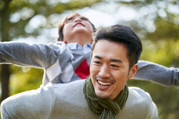 asian father and son having fun outdoors in park