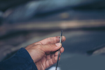 Car Mechanic man hand checking dipstick engine oil car mechanical on site service. Close up hand man check engine oil level Locate dipstick, wipe clean, check dipstick level before fill up engine oil