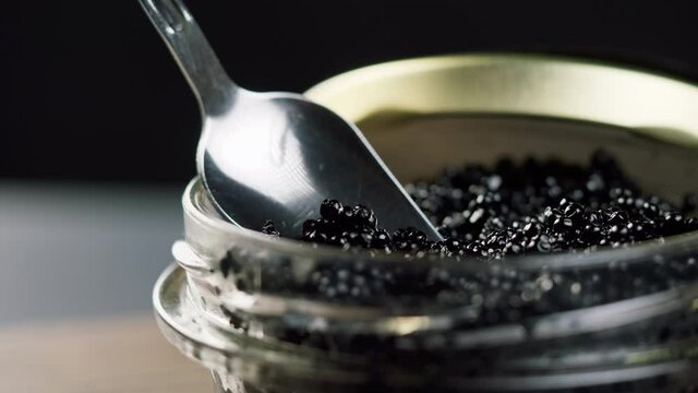 Black caviar close-up. Beluga sturgeon salted roe in glass bowl. Raw seafood. Luxury delicacy food. Delicious and tasty fish products. Russian cuisine. Festive dinner.