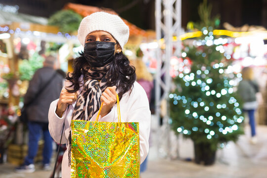 Woman in protective mask with paper shopping bags at Christmas fair