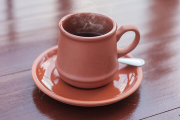 mug of hot coffee or tea on wooden table in the morning with mountain and nature background