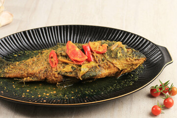 Ikan Pesmol or Pesmol Fish with Yellow Curry, Close Up on Wooden Table with Copy Space for Text