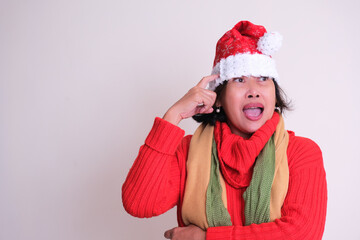 Woman in red warm clothes pointing at her Santa's hat she is wearing