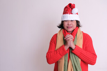 Asian woman wearing red warm clothes and Santa's hat, praying on Christmas