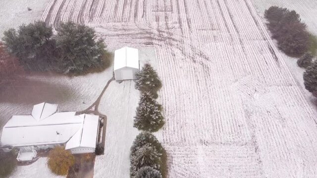 Slow motion top view of the Snowy Farmland in Southeast Michigan with building, trees and land frozen in snow in USA.