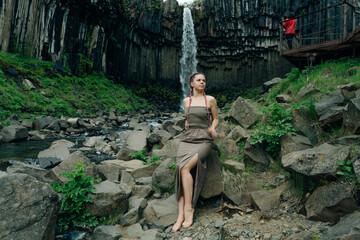 beautiful girl in a dress next to Svartifoss waterfall in the Skaftafell National Park, iceland