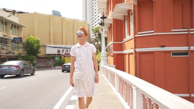 Portrait of Confidence Asian guy drag queen wearing woman clothes with sunglasses walking down city street in sunny day. Diversity sexual equality, lgbtq pride and transgender cross-dressing concept