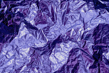 creased shiny metal foil sheet in trendy very dark velvet lilac violet color. Background or peri backdrop. Monochrome