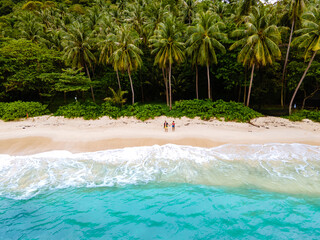 Freedom beach in Phuket Thailand. tropical beach with palm trees and white sandy beach, couple man and woman at beach from above, drone aerial view - obrazy, fototapety, plakaty