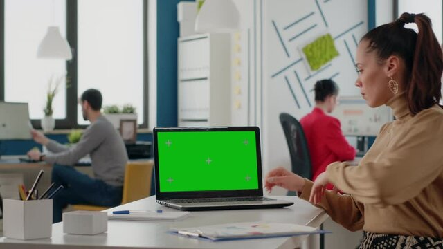 Person working with green screen on laptop in business office. Woman employee using computer with isolated mock up background and chroma key template on display. Blank copy space screen