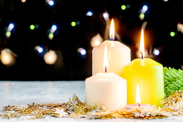 black Christmas background with colorful lights burning candles and decorative snowflakes in the foreground