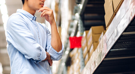 Portrait of smiling asian engineer man order details checking goods and supplies on shelves with goods background in warehouse.logistic and business export