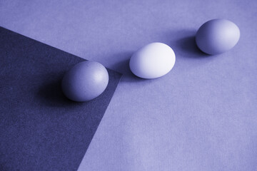 The color of 2022. Abstract background painted in a fashionable color.Three chicken eggs are laid on paper.