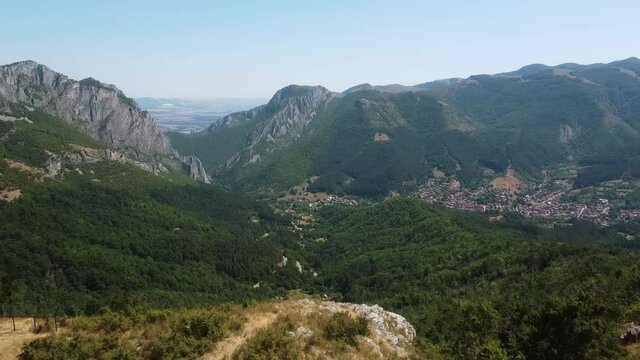 Wooded rocky mountain landscape aerial view revealing tourist man taking photo backward flying drone shot