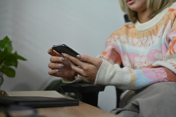 Young asian woman using smart phone while siting living room.