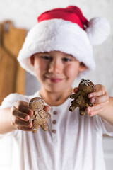 Smiling little child shows funny gingerbread men prepared for Christmas holiday