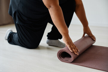 Close up of black senior woman unrolling yoga mat while exercising in studio, copy space - Powered by Adobe