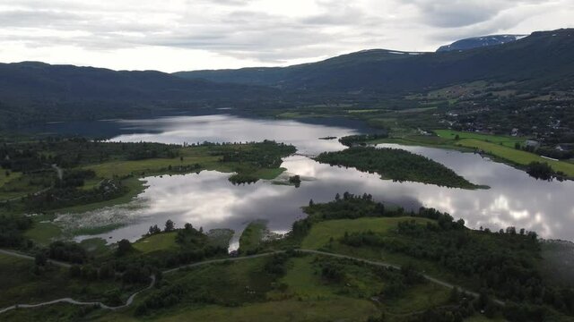 Popular Ustedalsfjorden lake at Geilo - Backward moving aerial at dawn with sky reflections in water surface - Norway