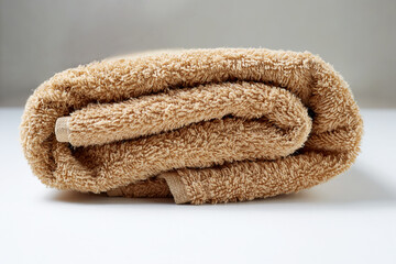 Obraz na płótnie Canvas a rolled up brown towel is a hygiene and body care item