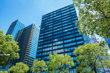 Fototapeta premium Modern office building with glass facade on a clear sky background. Transparent glass wall of office building.