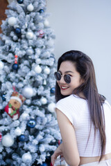 portrait of beautiful girl wearing sunglasses and christmas tree as background