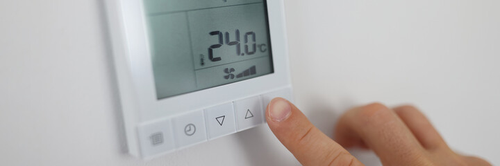 Person regulates air temperature in room through remote control on wall