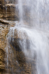 Waterfall texture. Background of the falling purest mountain water. A cascade of blurred motion. Natural abstract background for design. The concept of life, ecology, environmental protection.