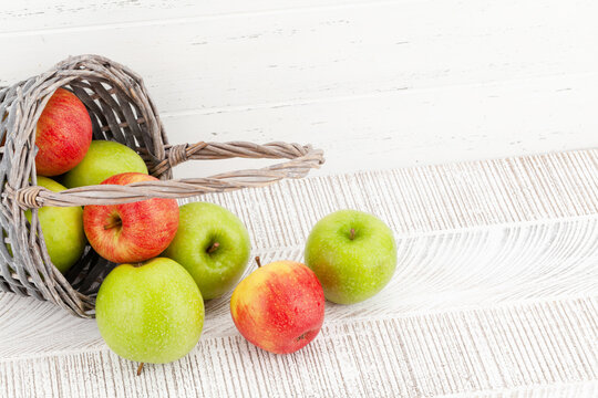 Fresh ripe apples in basket on wooden table