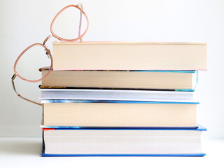 Stack of books and glasses on table, on white background.	