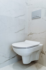 Toilet is suspended in the modern apartments. Marble latrine, white interior. Separate restroom with amenities