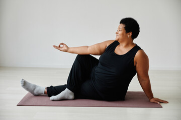 Full length portrait of active senior woman enjoying yoga indoors and smiling