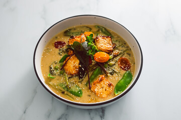 vegan thai green curry with pan fried silken tofu and freshly picked vegetables, healthy plant-based food