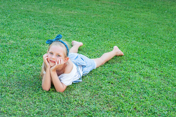 Little girl lying on green grass