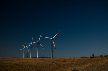 Modern windmills in land against blue sky. Shot in Castilla La Mancha, Spain