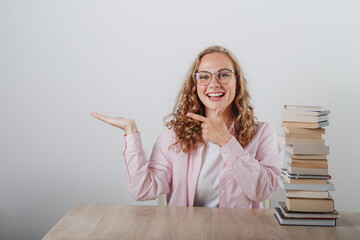 a girl looks at a large stack of books