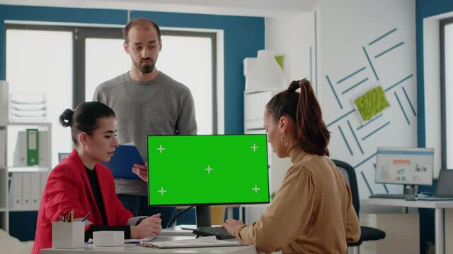 Business people working on computer with green screen in startup office. Colleagues doing teamwork and discussing about isolated chroma key with mockup template and background on display.