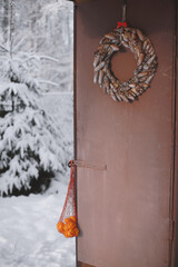 Tangerines in a bag are hanging on an old door.