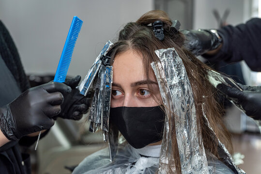 lightening dark hair with paint to further give a different color in the beauty salon.