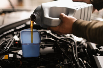 Obraz na płótnie Canvas A man pours engine oil from a canister into a car