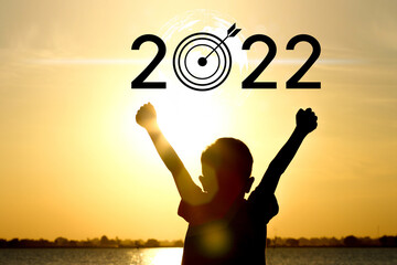 Happy new year 2022. Silhouette of child on seacoast in sunset.