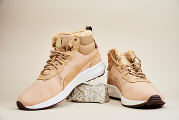 Male boots on beige background. Pair of winter shoes on stone platform